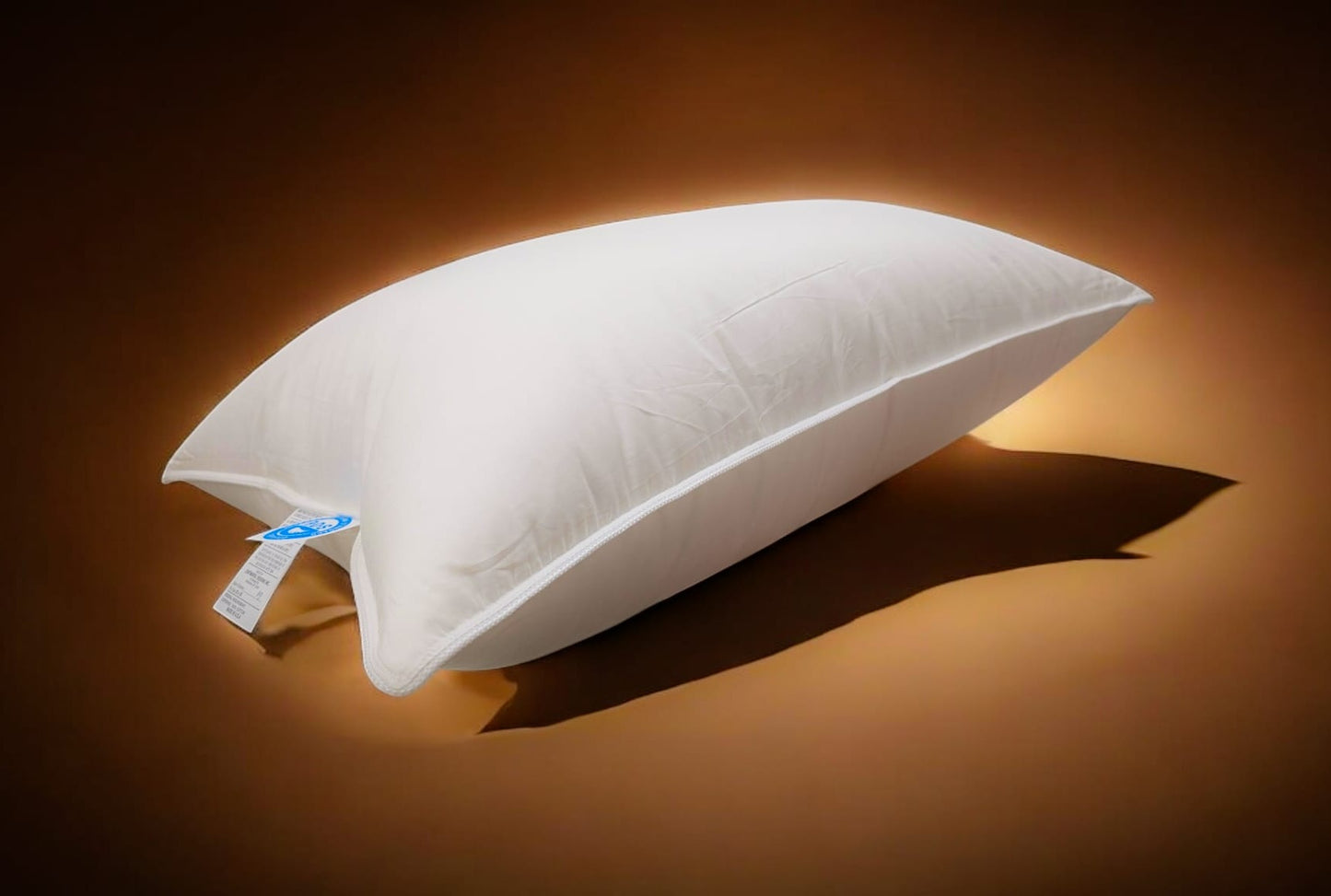Premium Polish goose down pillow with cotton shell, softly lit against a warm brown background with visible product tags.