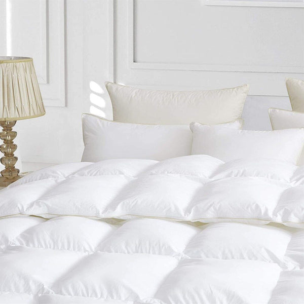A close-up of a plush white duvet with baffle box construction, resting on a bed with matching pillows in a bright, elegant bedroom, highlighting its softness and loft.
