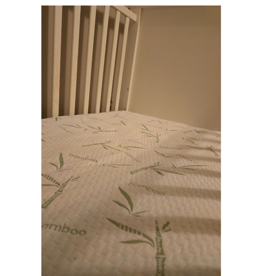 Close-up view of a bamboo mattress protector on a crib mattress, showcasing the breathable and soft bamboo fabric.