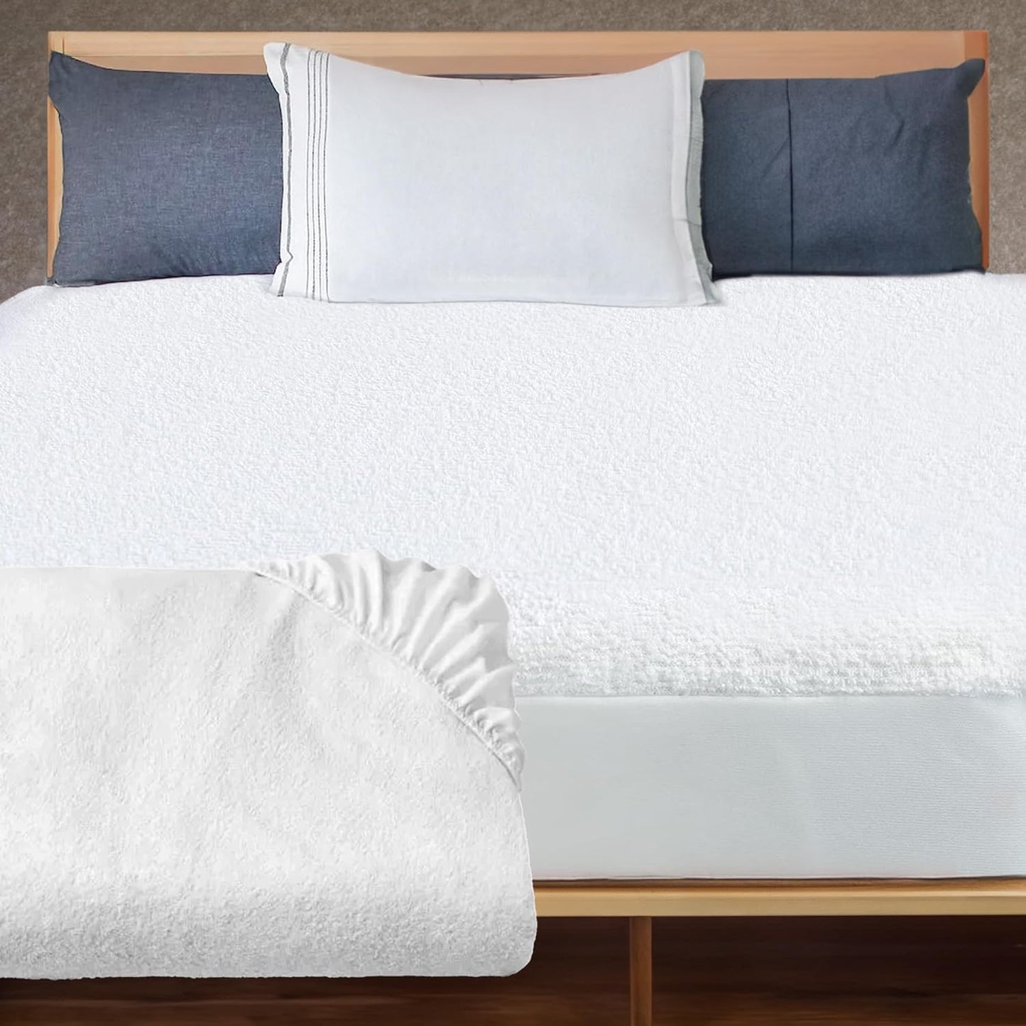 A neatly made bed showcasing a white terry cloth mattress protector with a snug fit around the mattress, enhancing bedroom aesthetics