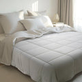 A modern, minimalist bedroom with a bamboo bedding set in a neutral color, featuring a plush comforter and matching pillowcases.