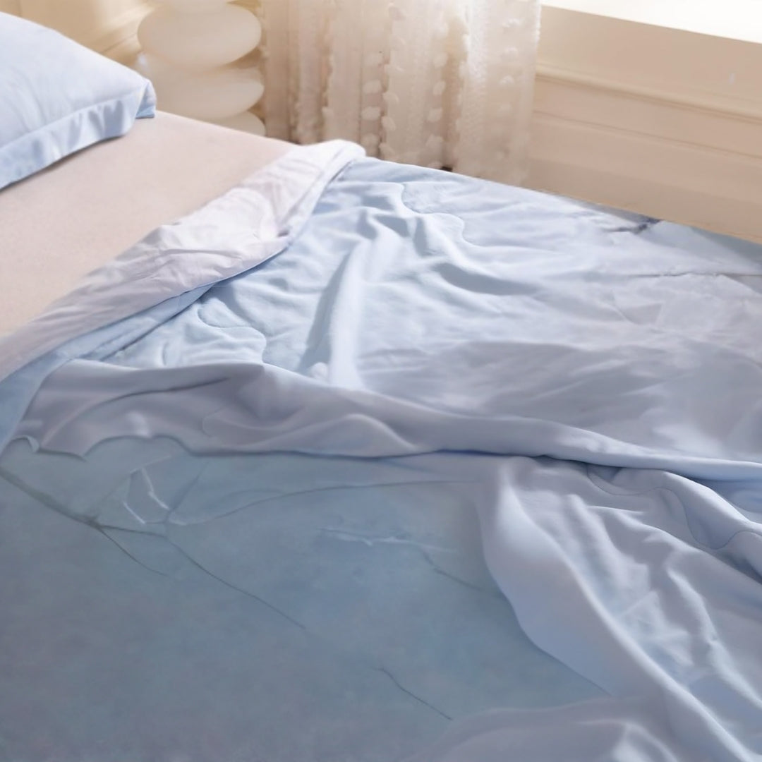 Wrinkle-resistant cooling bamboo sheets in light blue, draped casually on a bed near a window with soft natural light and textured curtains.

