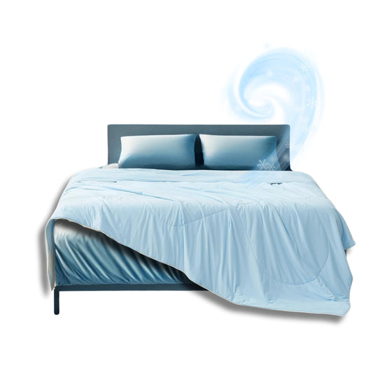 Light blue cooling comforter and pillow set on a modern bed with a swirl of cool air and snowflake graphics suggesting breathable, temperature-regulating fabric.