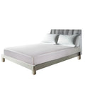 Modern bedroom featuring a minimalistic bed with a sleek gray upholstered headboard and a white mattress protected by a textured waterproof mattress protector, set on a simple metal frame. The neutral color palette provides a calm and clean sleeping environment