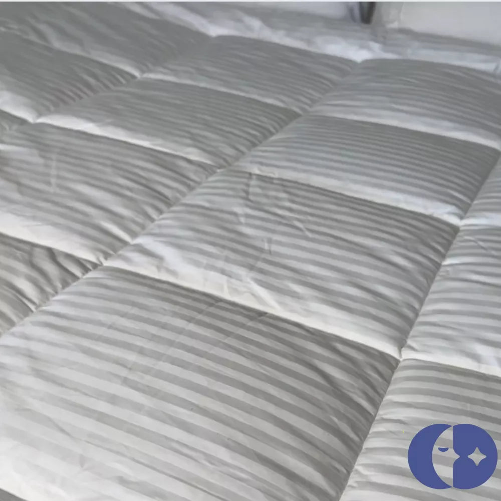 Detailed view of a baffle box stitched white duvet with subtle stripes, showcasing its plush fill and Continental Bedding logo.

