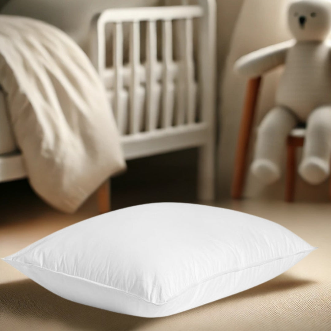 A toddler pillow placed in a nursery setting, with a soft, neutral-toned background featuring a crib and a plush teddy bear, emphasizing comfort and safety.